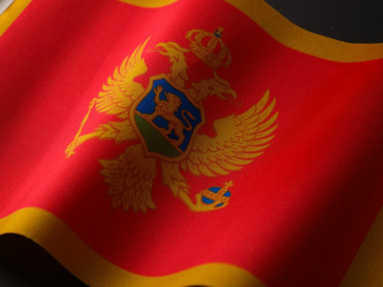 Close-up of Montenegro's national flag with emblematic coat of arms, highlighting texture and symbolism.