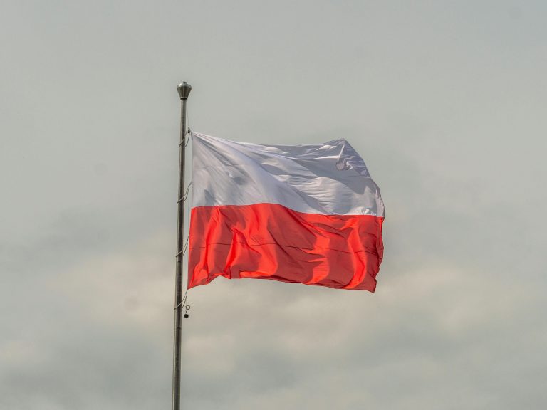 The Polish national flag waving prominently against a cloudy sky, showcasing patriotic pride.