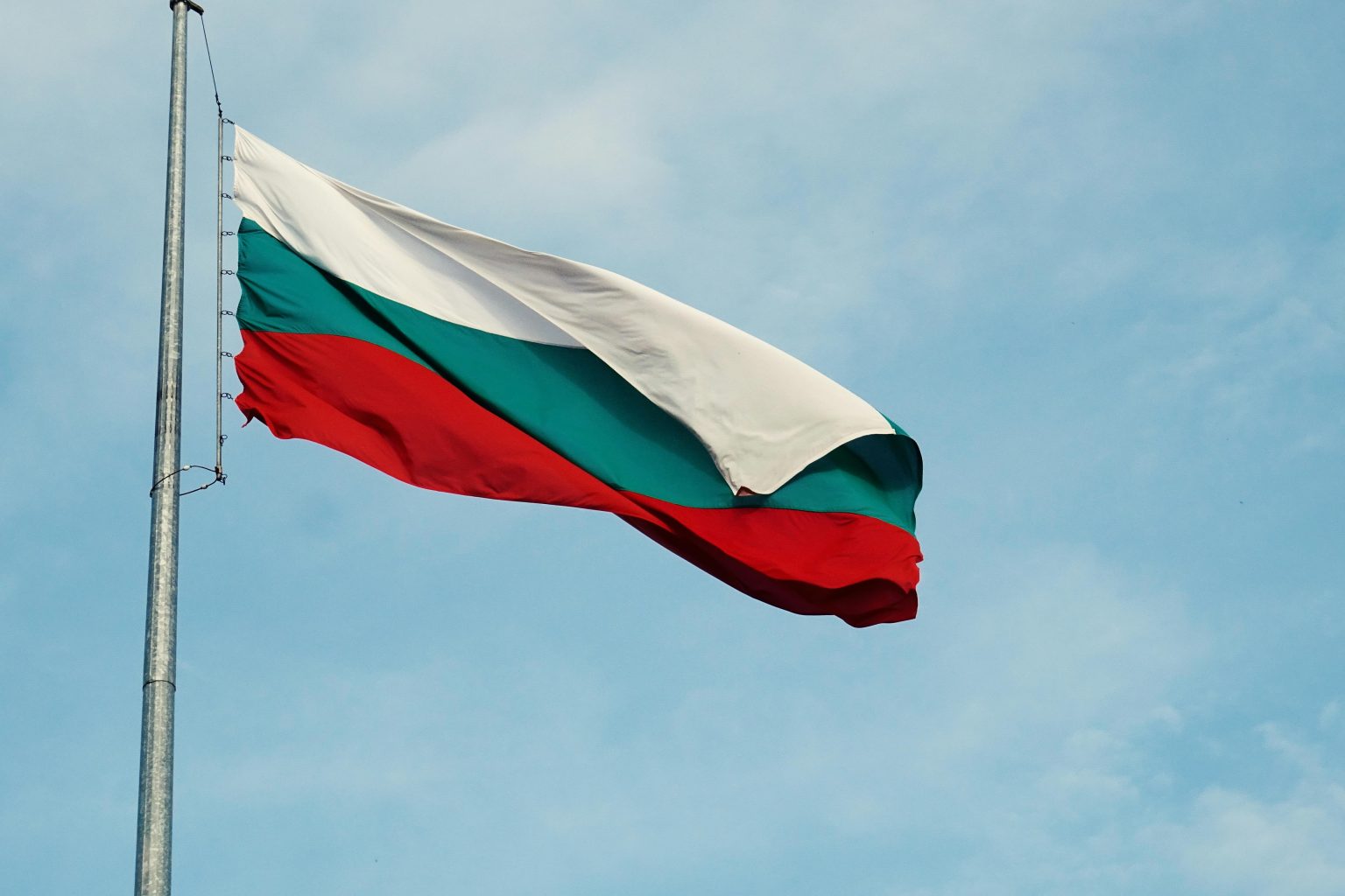 The national flag of Bulgaria waving on a flagpole against a clear blue sky in Varna.
